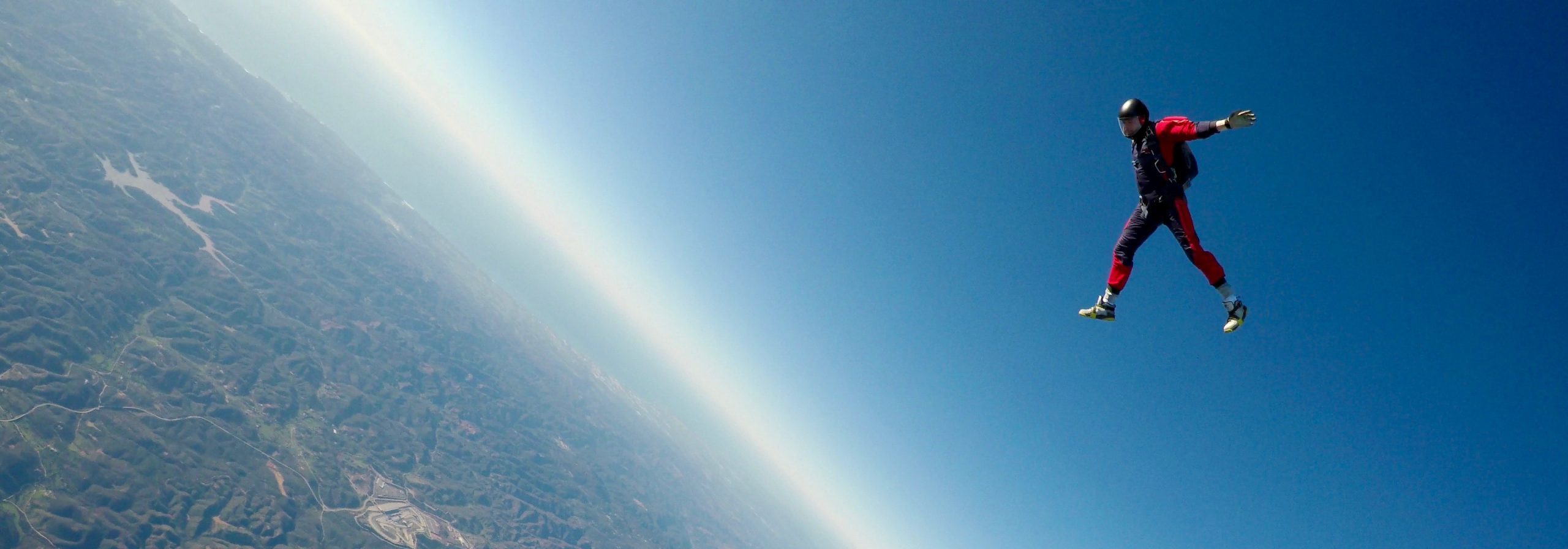 A person wearing a red suit flying high above.