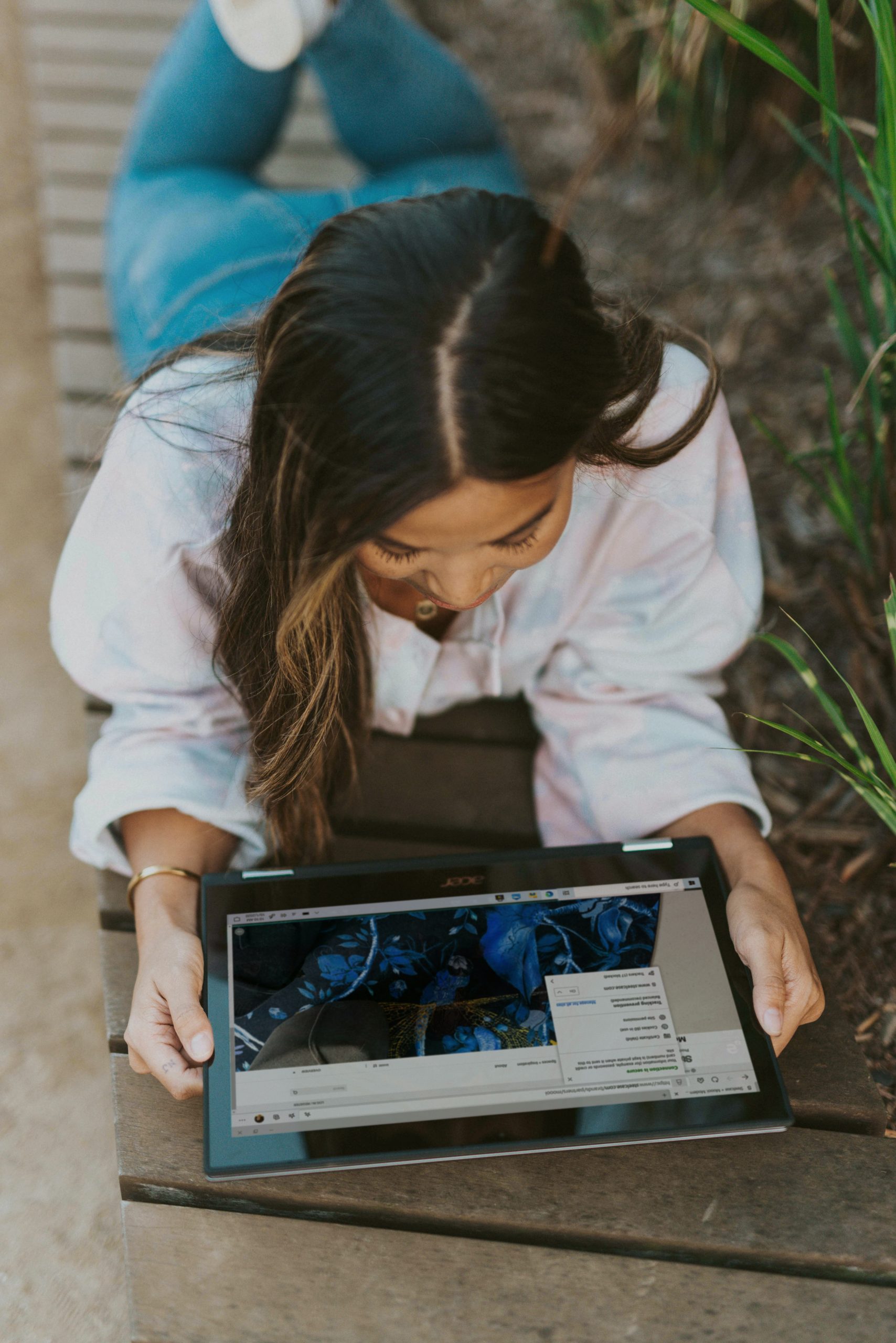 Woman using tablet while seated on bench.